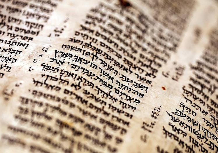 Imagen principal - En la imagen superior, detalle de una de las páginas del 'Codex Sassoon'; debajo, uno de los empleados de Sotheby's muestra la biblia a los posibles compradores; por último, una vista de la sala de subastas en Nueva York durante la puja.