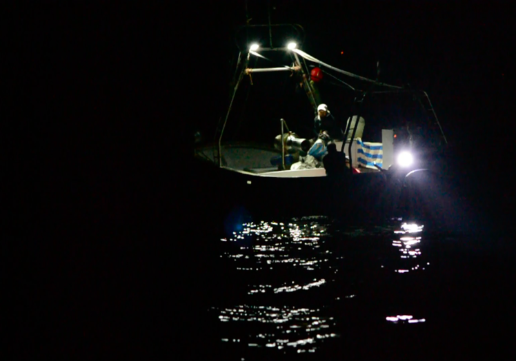 Barco marroquí lanzando red de pesca a la deriva.