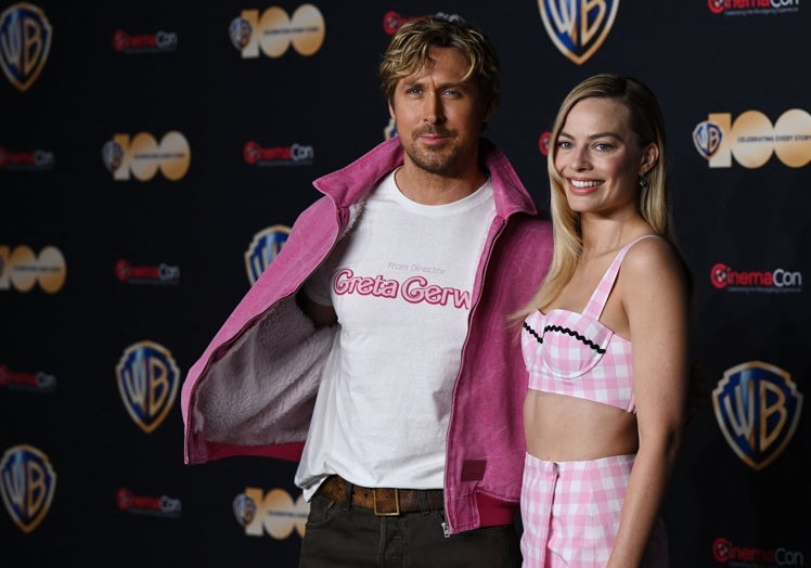 Ryan Gosling junto Margot Robbie vistiendo una película con el nombre de Greta Gerwig