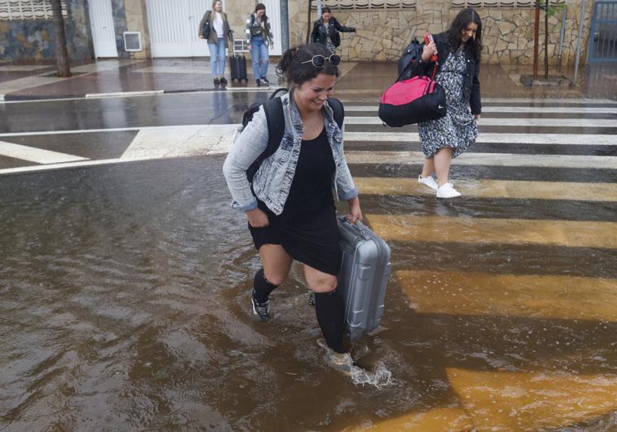 Varias personas cruzan una calle inundada en Benicasim (Castellón).