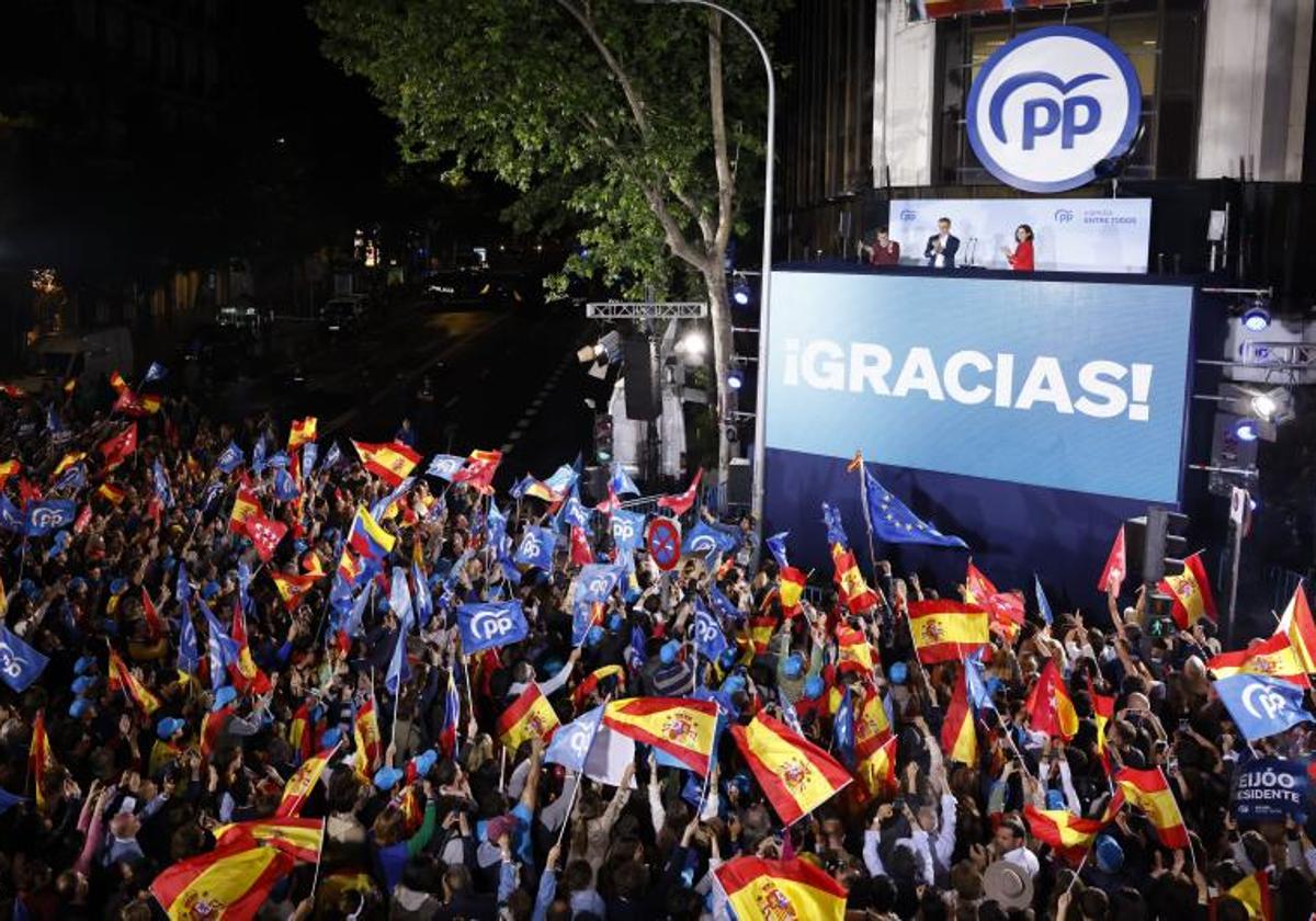 Ayuso, Almeida y Feijóo saludan desde el balcón de Génova tras conocer los resultados electorales.