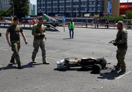 Tres agentes de policía caminan junto a la parte de un misil que ha aterrizado en una calle de Kiev durante un ataque ruso