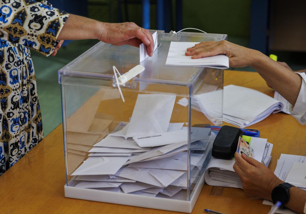 Una mujer introduce su voto en una urna.