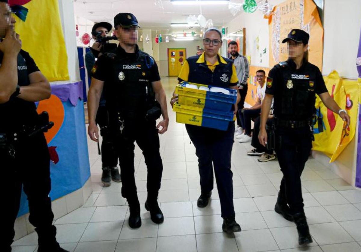 Varios agentes escoltan a una funcionaria de Correos con votos a una mesa electoral.