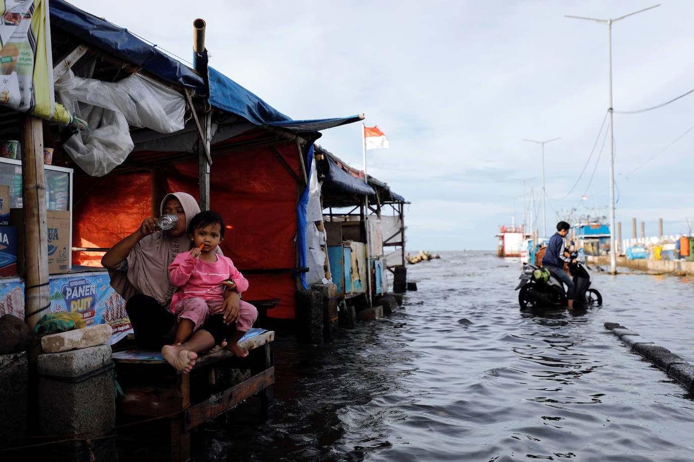 Imagen - Zuriati, junto a su hija Syifa, en el puesto donde trabaja en el puerto yakartés de Muara Angke, inundado por las mareas altas.