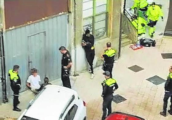 Ertzaintza y policías locales detienen al joven que lanzó el sofá mientras los sanitarios atienden a la víctima.