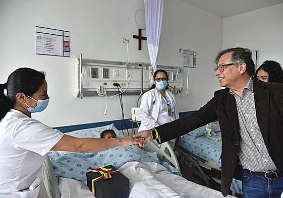 El presidente de Colombia, Gustavo Petro, saluda a una sanitaria en la habitación de uno de los niños.