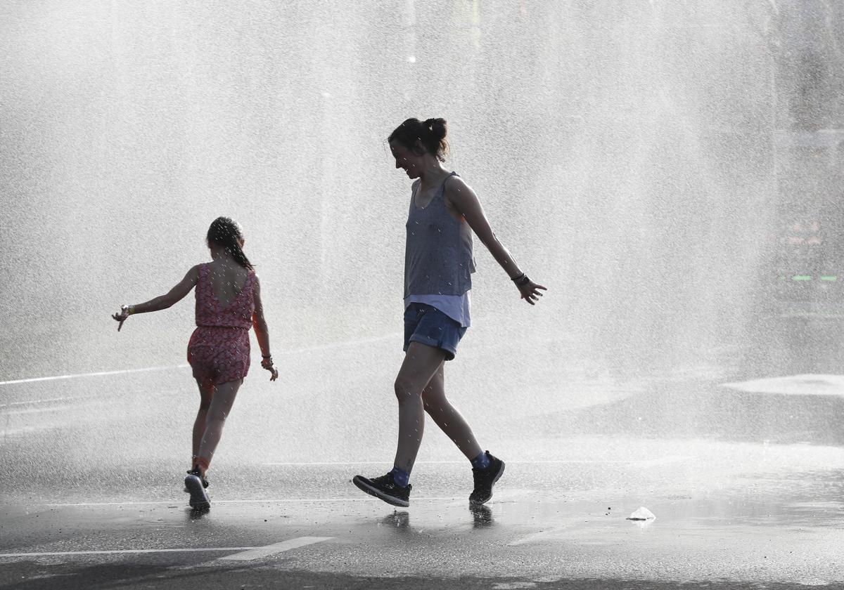 Unas jóvenes se refrescan en una fuente.