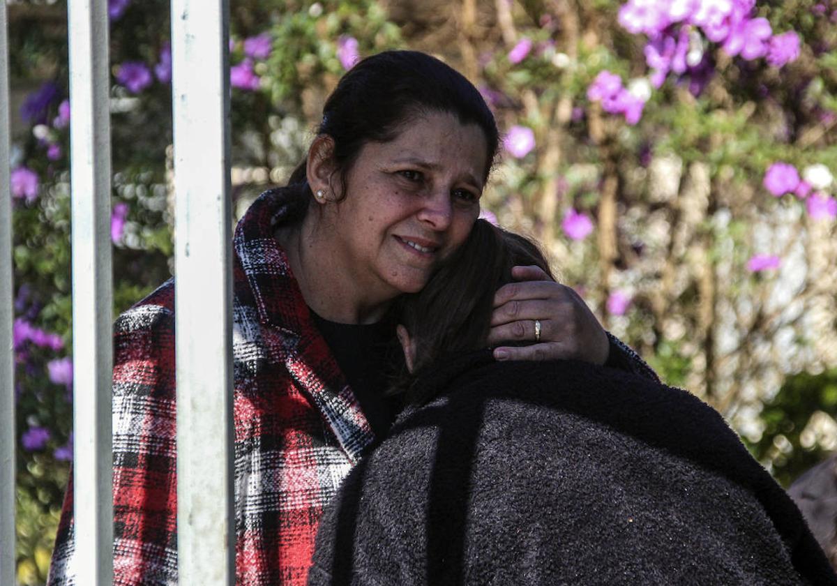 Dos personas se abrazan en la entrada a la escuela Profesora Helena Kolody, donde dos jóvenes fueron asesinados por un exalumno, en Brasil