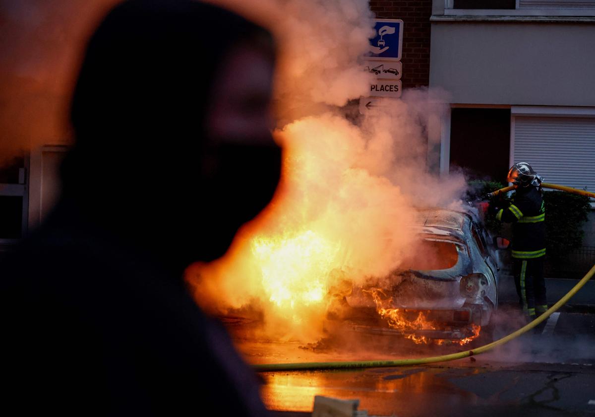 Un manifestante pasa frente a un coche incendiado en Lille durante las protestas.