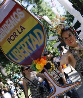 Imagen secundaria 2 - En la imagen superior, la cabecera política de la marcha del Orgullo en Madrid celebrada este sábado; debajo, varias de las personas que participaron en una jornada con marcado signo reivindicativo y, por último, una persona exhibe un curioso cartel con un lema elocuente.