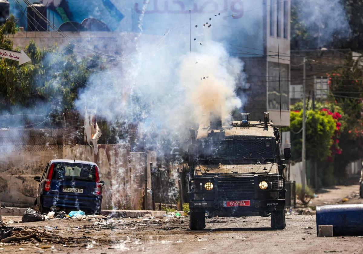 Un vehículo blindado israelí dispara gas lacrimógeno durante una operación militar en Yenín.