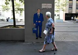 Una mujer pasa junto a una pintura mural que representa a Silvio Berlusconi.