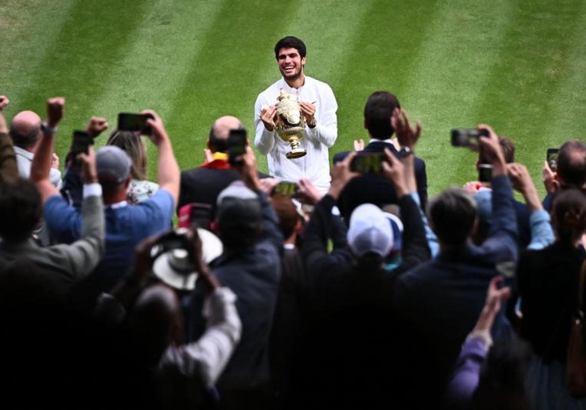 Carlos Alcaraz sostiene el trofeo de Wimbledon ante el público londinense.