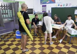 Un hombre acude a votar a un colegio electoral de Almería con la sombrilla y la nevera de playa