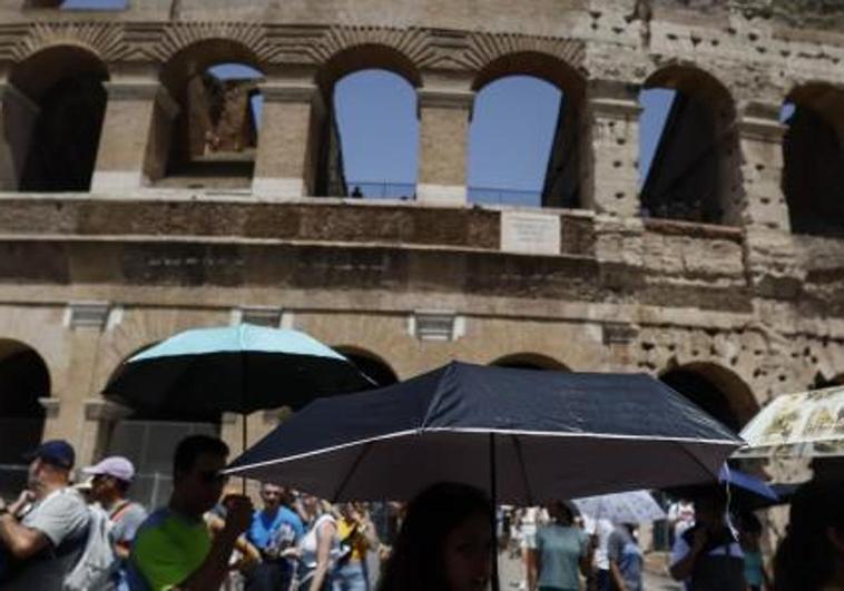 Paseantes se protegen del intenso calor en el centro de Roma, donde el mercurio ha llegado este miércoles a los 43 grados.