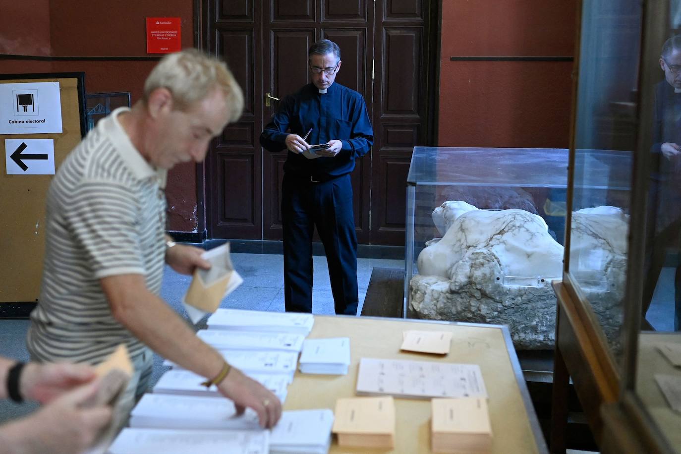 Un sacerdote prepara sus papeletas en un colegio electoral en Madrid.