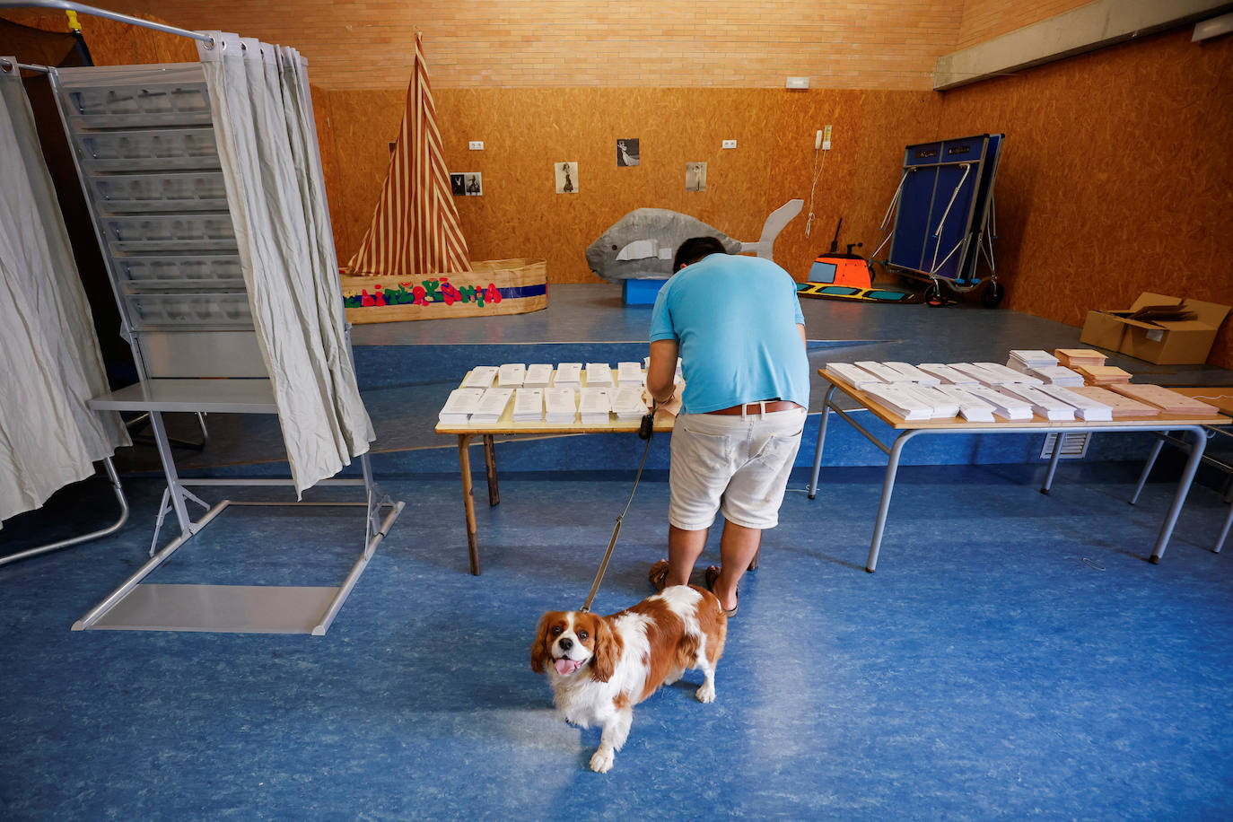 Una persona con un perro recoge una papeleta para emitir su voto en un colegio de Barcelona. 