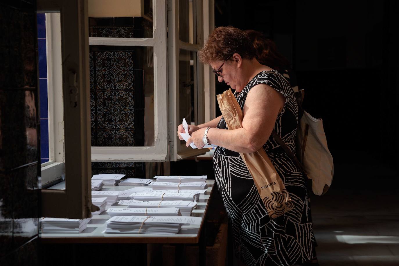 Una mujer escoge una papeleta en un colegio electoral de la Comunidad Valenciana.