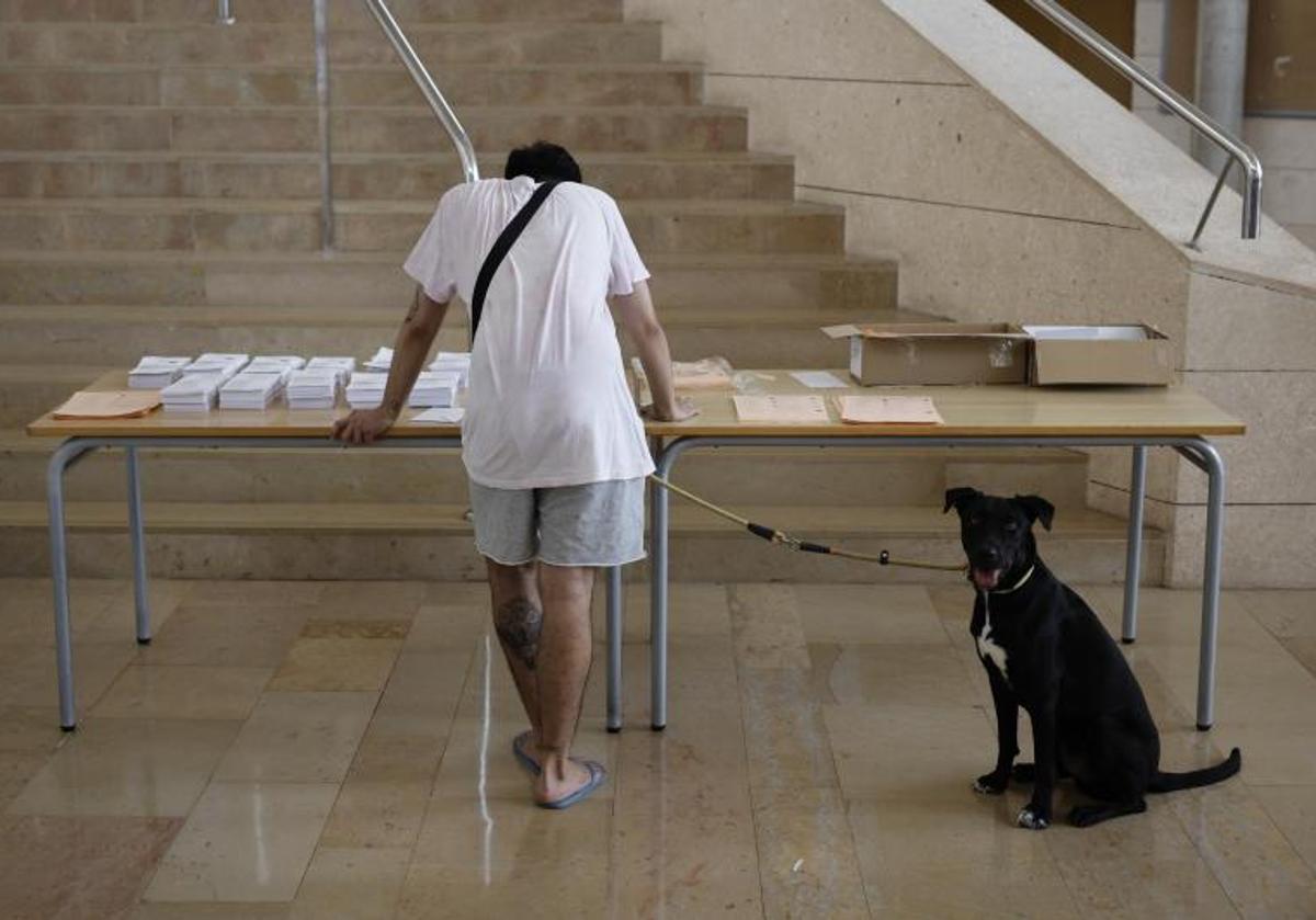 Una persona escoge la papeleta para votar durante la jornada electoral.