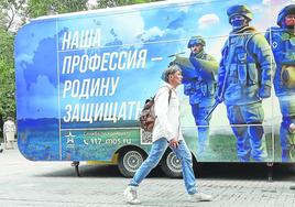 Dos transeúntes pasan junto a una oficina de reclutamiento móvil instalada en una calle de Moscú.