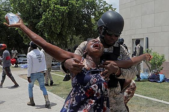 Un policía sostiene a una mujer frente a la embajada norteamericana en Puerto Príncipe.
