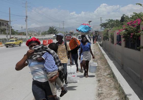 Varias personas caminan con sus pertenencias en Haití.