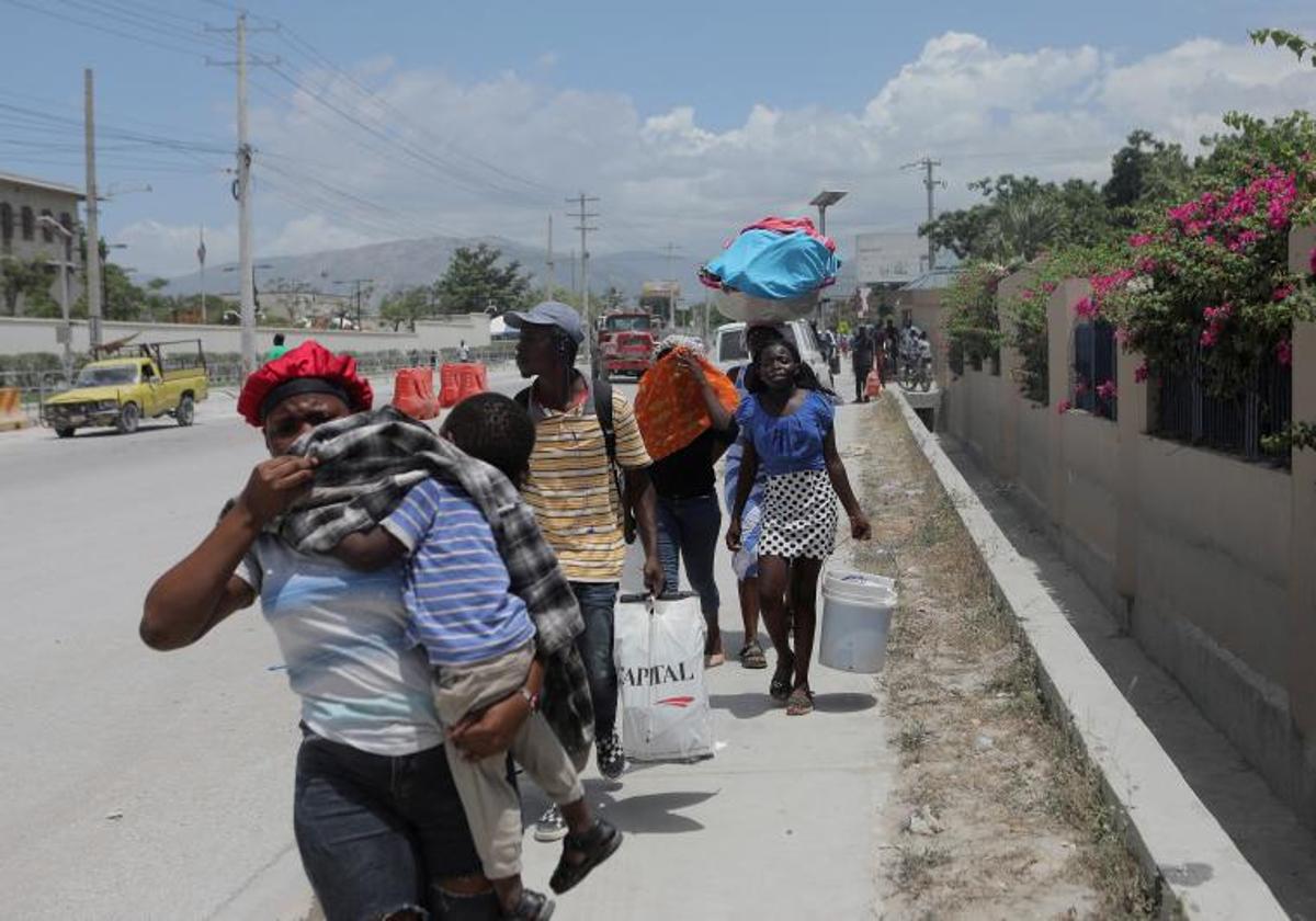 Varias personas caminan con sus pertenencias en Haití.