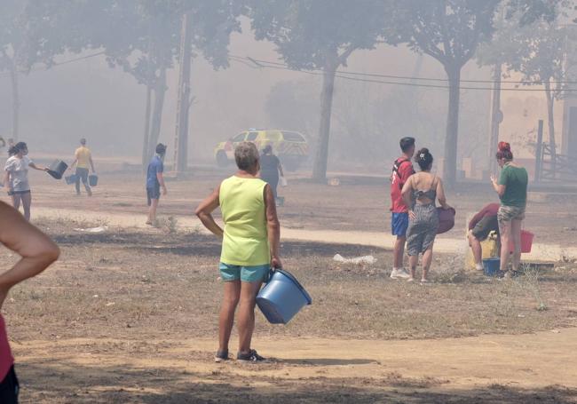 Decenas de vecinos intentaron colaborar en las labores de control echando agua con cubos para humedecer las zonas que podían arder más cerca de sus casas.