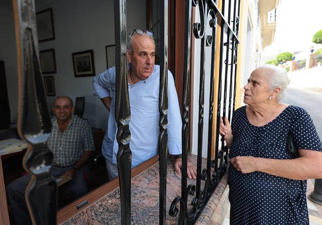 Juan Manuel Bravo y su madre, María Moral, hablan a través de la celosía de la ventana del despacho que este abogado mantiene abierta mientras trabaja, siempre que la sombra proteja su calle.