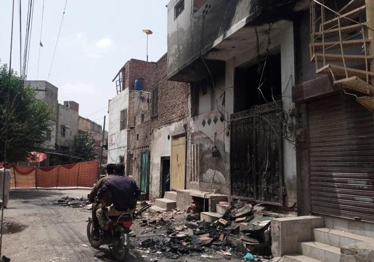 Policías patrullan junto a casas incendiadas después de que turbas atacaran iglesias y viviendas cristianas en la localidad de Jaranwala.