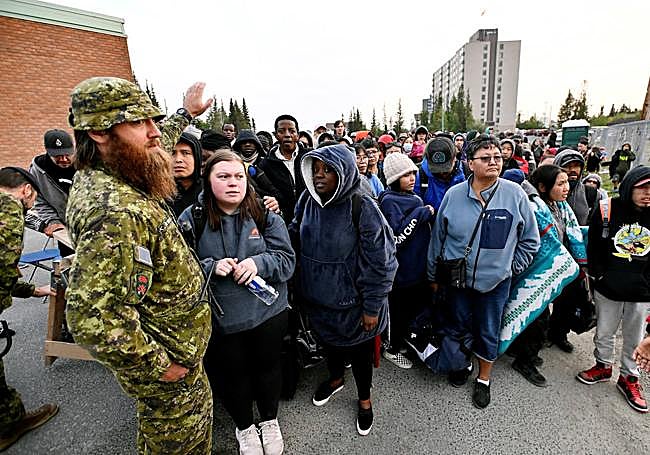 La gente hace fila afuera de una escuela local para registrarse para ser evacuada de Yellowknife