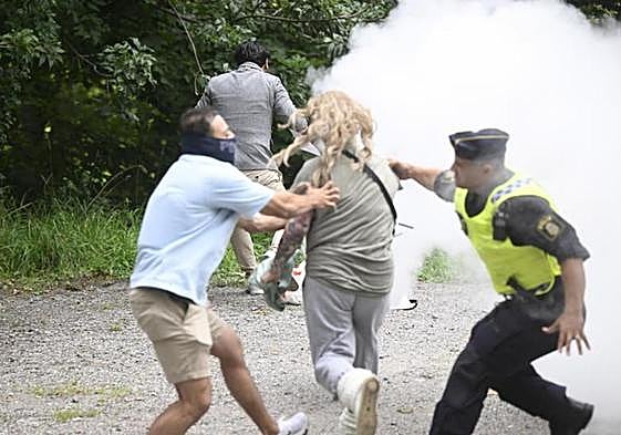 Un policía sueco ìntercepta a la mujer que este viernes intentó impedir una nueva quema del Corán.