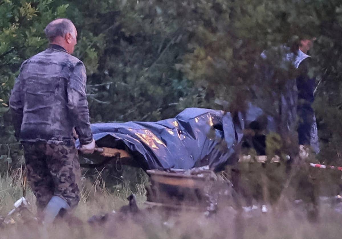Dos miembros de los equipos de emergencias transportan una bolsa para cadáveres cerca de los restos del avión privado vinculado al jefe de los mercenarios de Wagner, Evgeny Prigozhin