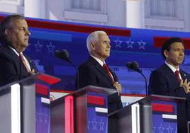 El exgobernador de Nueva Jersey, Chris Christie, el exvicepresidente Mike Pence y el gobernador de Florida, Ron DeSantis, se llevan las manos al corazón durante el juramento a la bandera de Estados Unidos al comienzo del primer debate de candidatos republicanos.