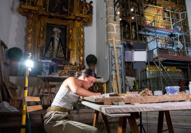 Mara, una de las tres restauradoras del retablo de la iglesia de La Asunción de Nombela, concentrada en su trabajo.