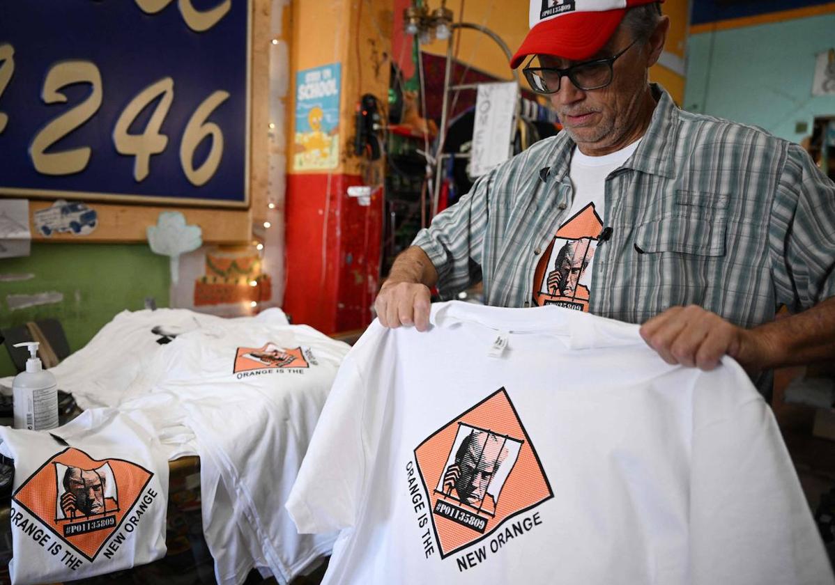 El propietario de una tienda dobla camisetas con fotografías policiales de Trump