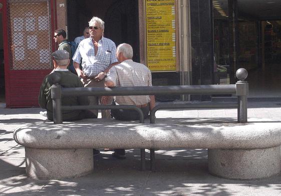 Tres jubilados conversan en un banco.