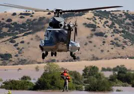 Un helicóptero y su tripulación trabajan para rescatar a una persona varadas en una zona inundada