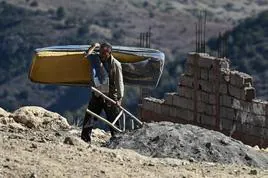 Un afectado por el terremoto carga con las mínimas pertenencias que ha encontrado entre los escombros de su casa.