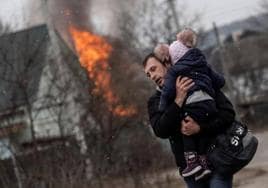 Un hombre y una niña escapan de las bombas en Irpin, en Ucrania