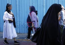 Las mujeres iraníes, algunas sin el velo obligatorio, caminan por una calle en Teherán