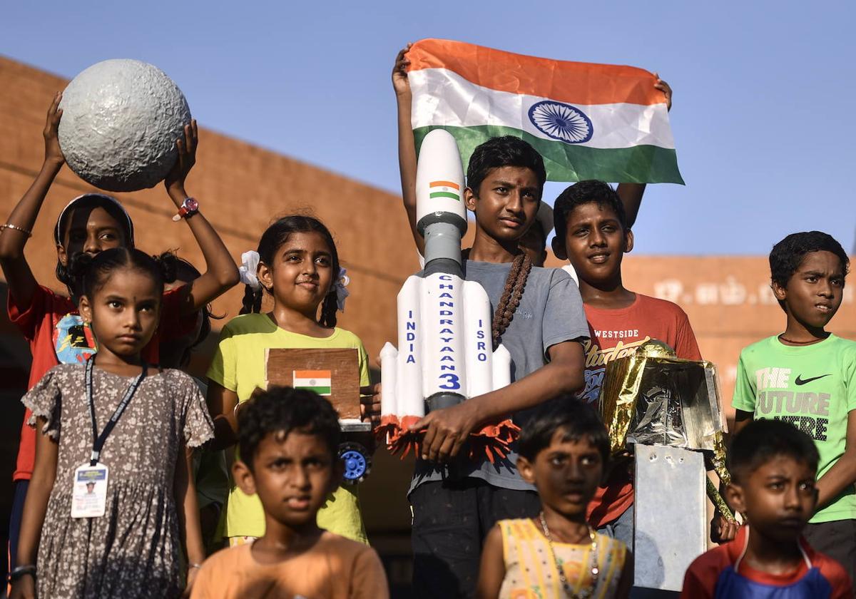 Niños indios con una maqueta del cohete que ha logrado llevar la sonda del país al polo sur de la luna.