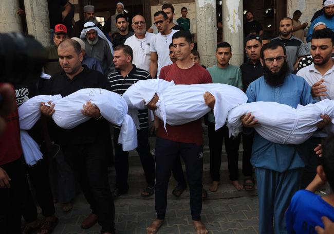 Un grupo de hombres porta los cadáveres de tres niños en la localidad de Rafah.