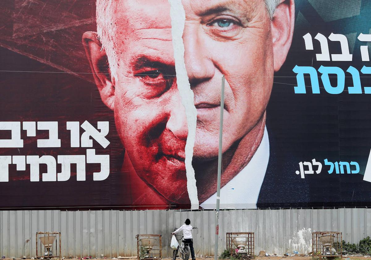 Un niño mira una pancarta de la campaña electoral del ministro de Defensa israelí, Benny Gantz, junto al primer ministro, Benjamin Netanyahu