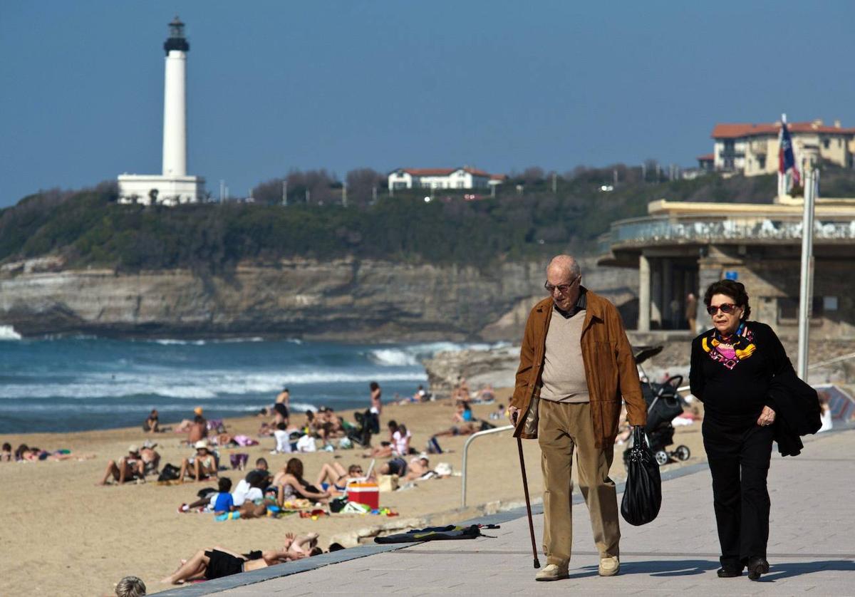 Una pareja de jubilados paseando por una playa.