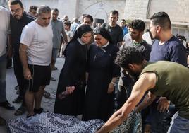 Dos monjas observan la retirada del cadáver de uno de los refugiados en el templo.