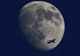 Un avión vuela con la luna creciente de fondo en Fráncfort, Alemania.