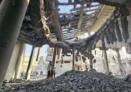 Los palestinos observan los destrozos causados por una bomba en un edificio en el norte de Gaza.