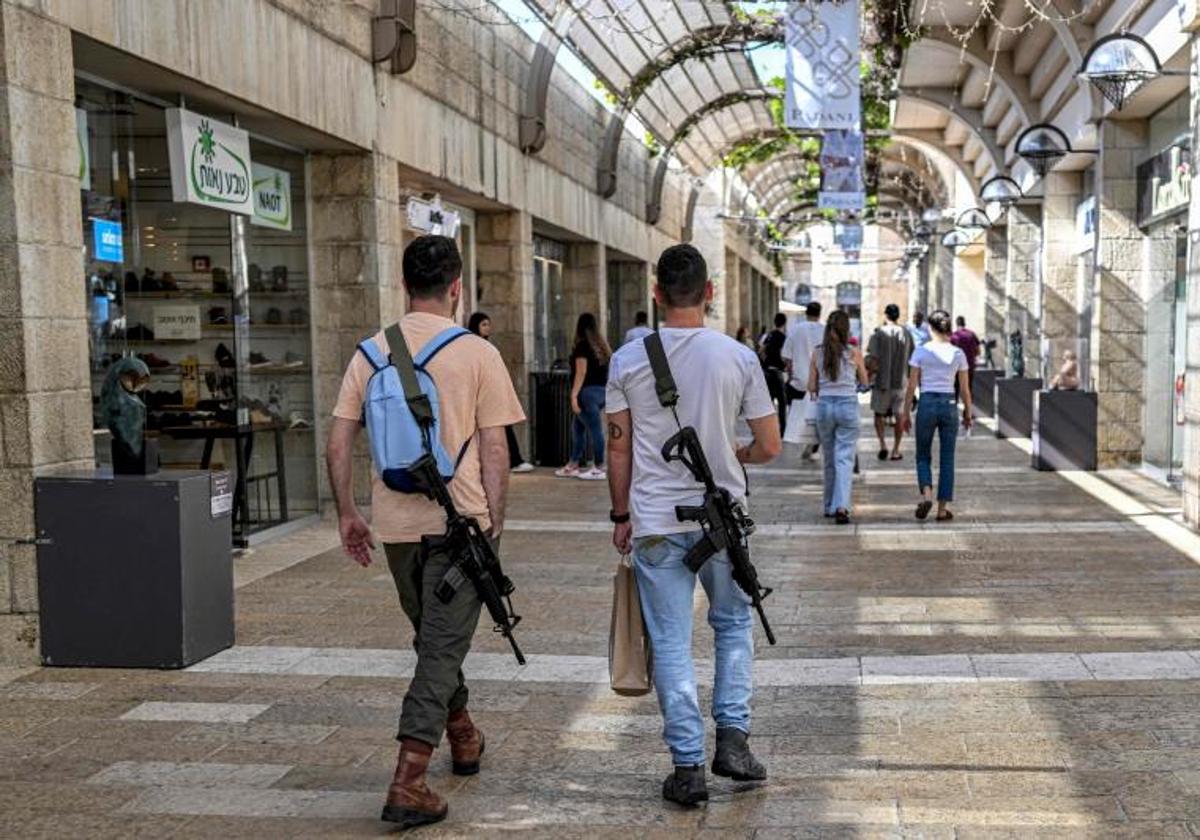 Hombres israelíes, armados con rifles de asalto automáticos M16 de fabricación estadounidense, caminan por un centro comercial en Jerusalén.